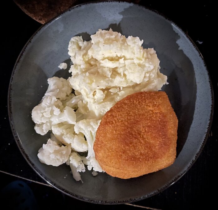 En tallrik med potatismos och en stekt panerad schnitzel, matservering, hemlagad måltid.