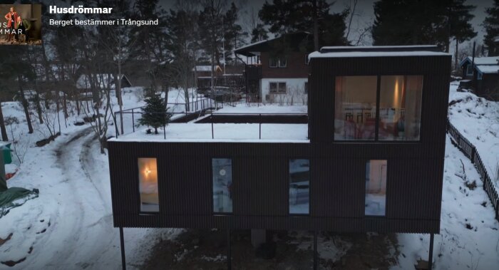 Modernt hus i vinterskymning, snö, träd, text "Husdrömmar" och "Bergbet bestämmer i Trängsund".