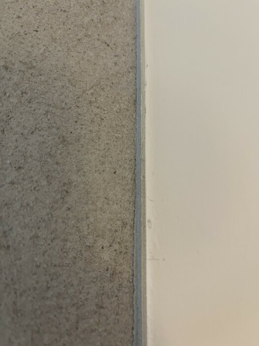 Grå betonggolv möter vit vägg med synlig skarv.
