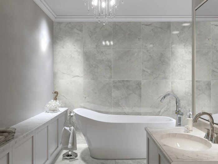 Modernt badrum med fristående badkar, marmorkakel, ljuskrona och dubbelhandfat.