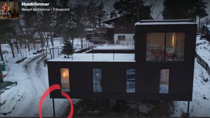 Modernt hus, snöig omgivning, röd cirkel markerar något, gråmorgon eller kväll, text "Husdrömmar".