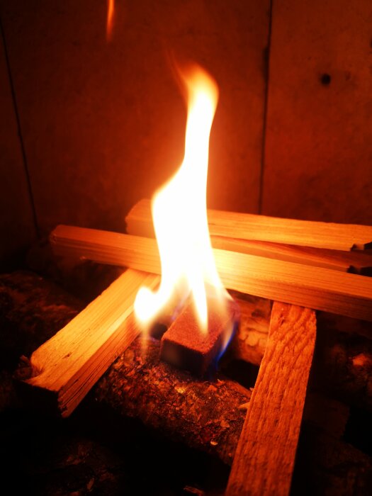 Eld med lågor brinner på trä och en tändkub i en spis.