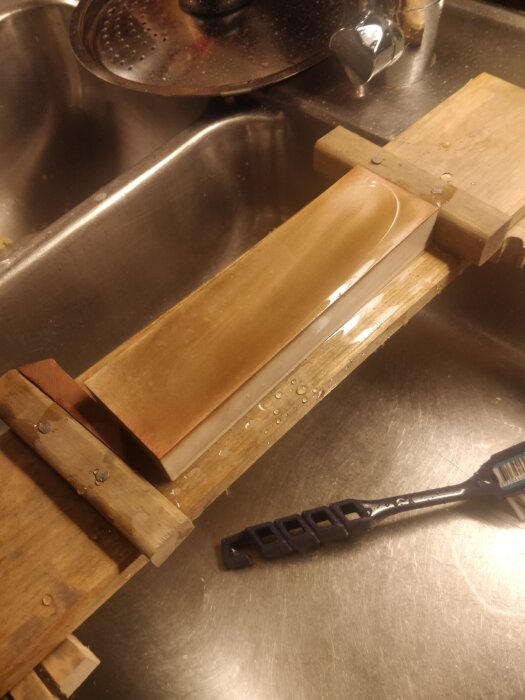 Slipsten för knivslipning på en diskbänk bredvid en svart tandborste.