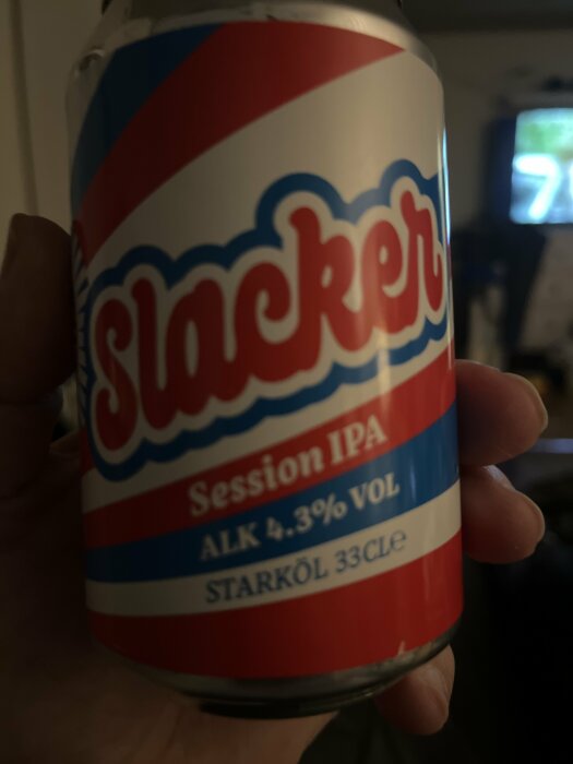 En hand håller en ölburk märkt "Slacker Session IPA" med 4.3% alkoholvolym och 33 cl storlek.