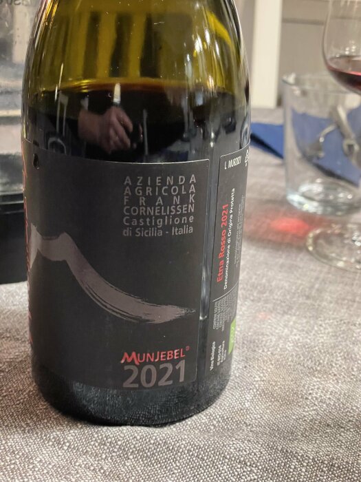 Flaskans etikett visar vin från Frank Cornelissen, Munjebel 2021, Castiglione, Sicilien, Italien. Vin och glas syns.