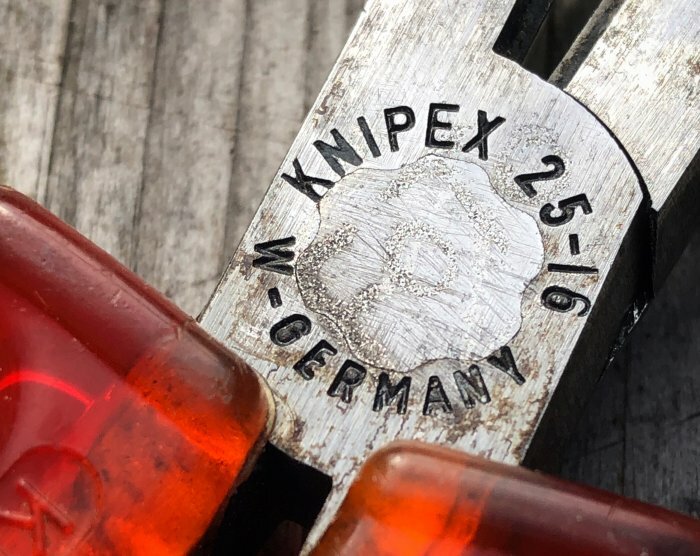 Närbild på trähandtaget av en gammal Knipex tång med inskriptionen "25-6" och "W.Germany".