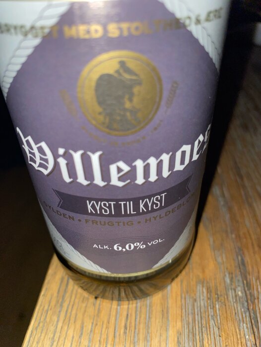 Närbild på en ölflaska märkt "Villemoes Kyst til Kyst" med 6,0% volymalkohol.