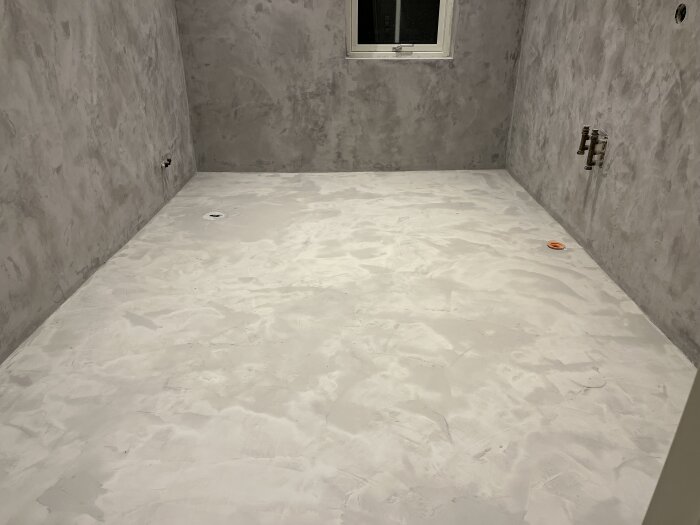 Rum med två lager epoxy på golvet och väggar med en omgång epoxy, oavslutad renovering.