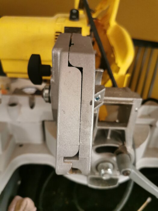 Närbild av en såg där en plastdel för kabelgenomföring saknas i änden av maskinen.