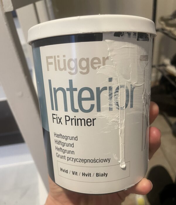 Burk med Flügger Interior Fix Primer i handen med spilld färg på sidan och skadat etikett.