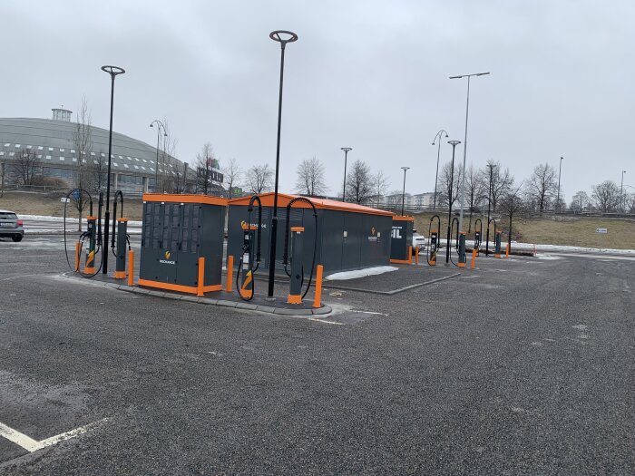 Elektriska fordonsladdningsstationer på en tom parkeringsplats, gråmulet väder, utan bilar som laddar.