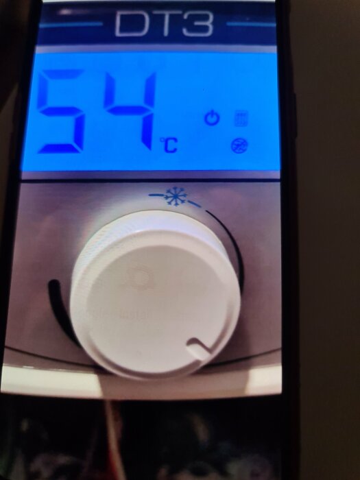 Digital varmvattenberedares display som visar 54 grader Celsius, under följs av ratt för temperaturinställning.