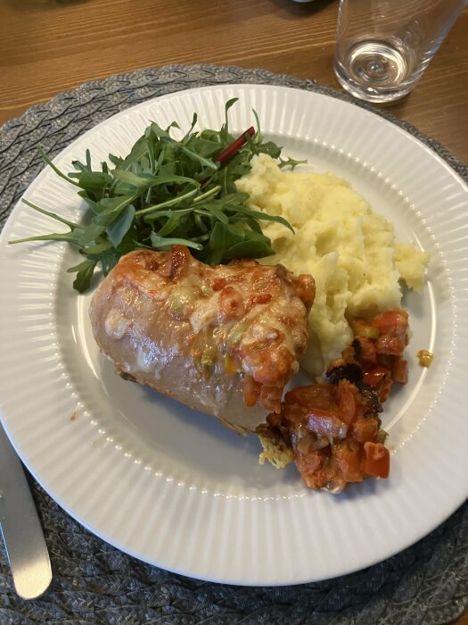 Ugnsbakad falukorv med ost och tomatsås serverad med potatismos och ruccolasallad.