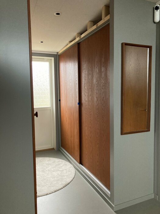 Egenbyggd garderob med MDF-dörrar, synliga skenor uppe och nere, i ett modernt rum.