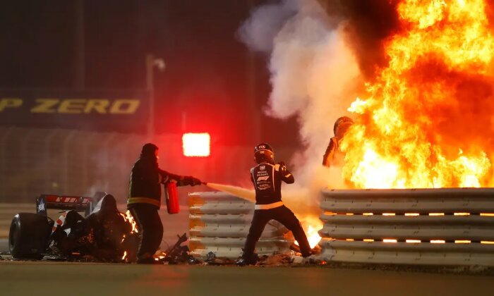 Racebil i lågor efter olycka med brandmän som bekämpar elden på en racerbana.