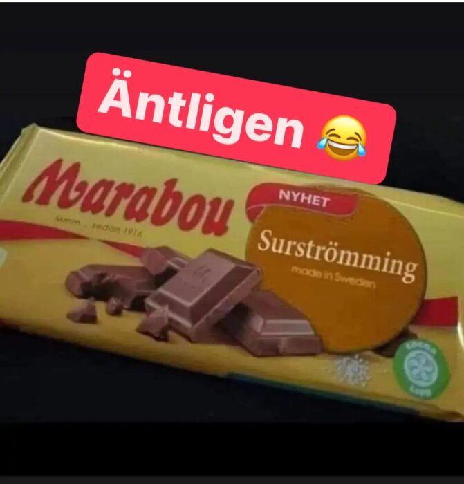 Chokladkaka märkt "Marabou Surströmming", bitar av choklad framför, "Äntligen" text och gråtande skratt-emoji.