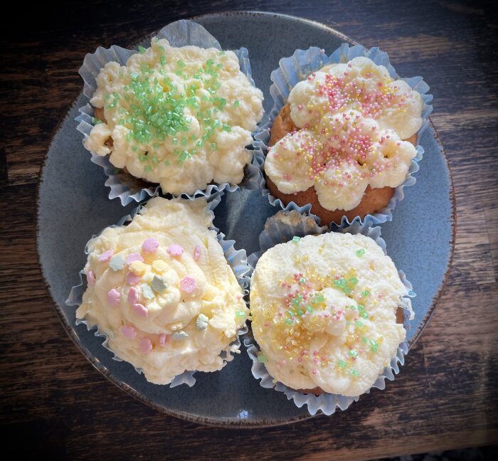 Fem frysta cupcake med glasyr och strössel på en tallrik.