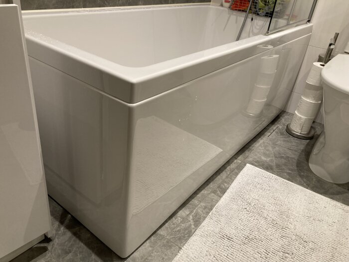Ett vitt hörnbadkar i en kaklad badrumsinteriör med synliga silikonlister vid kanterna.