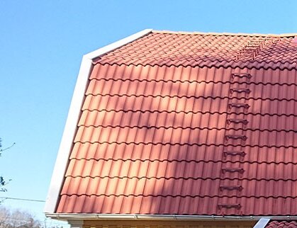 Rött betongtak med strukturerade takpannor på ett hus, dagtid under klart väder.