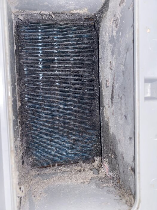 Förorenad värmeväxlare med ludd mellan lamellerna i en Samsung torktumlare.