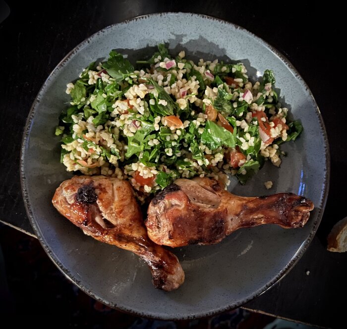 Kycklingklubbor och färgrik tabbouleh på en grå tallrik.