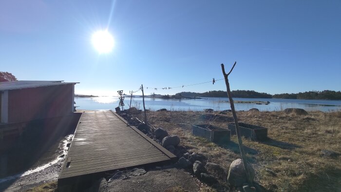 Solig kustmiljö med brygga, tvättlina och havsutsikt under fiberarbete.