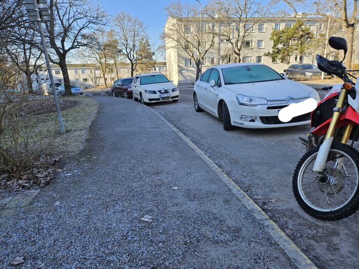 Bil felaktigt parkerad på trottoarkant med andra bilar i bakgrunden och en motorcykel i förgrunden.