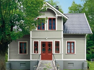 Hus med grå fasad, gräddvita foder och engelskt röda fönster och dörrar.