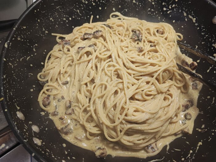 Spagetti Carbonara i stekpanna med prästost, ägg och bitar av bacon, utan grädde.