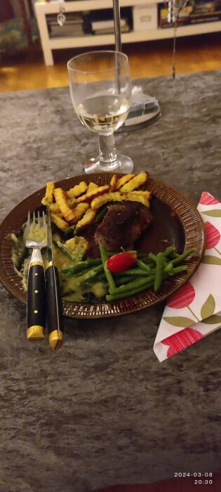 Mörad biff med bearnaisesås, pommes frites, haricots verts och cocktailtomat på en tallrik.