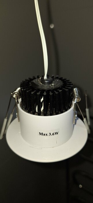LED-taklampa under installation, svart kylfläns, vit kabel, fjädrar för infästning, etikett "Max 3.6W".