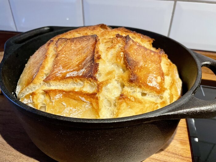 Nybakat bröd i en svart gjutjärnsgryta på ett köksbord.