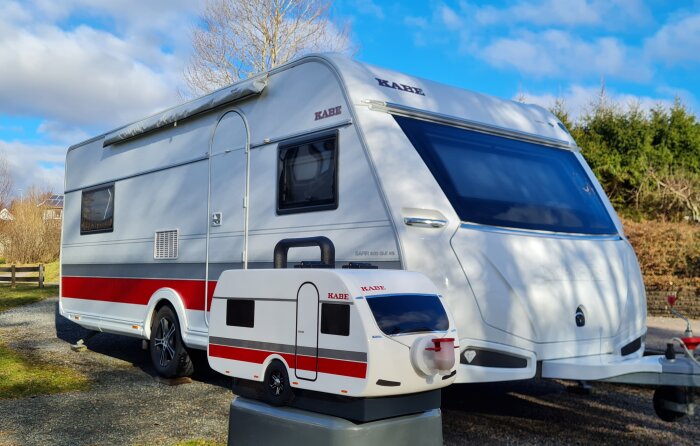 En stor och en liten husvagn modell KABE parkerade bredvid varandra i dagsljus.