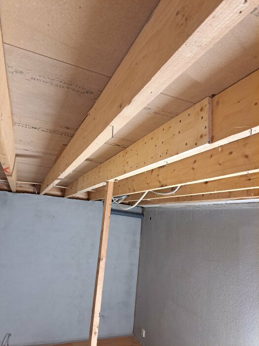 Installation av 18mm plywood på takstolar i ett renoveringsprojekt med synlig domkraft och stödbjälke.