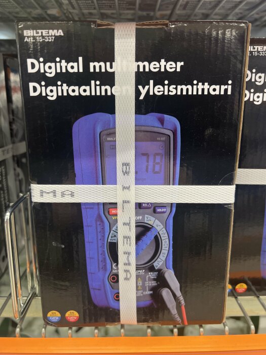 Digital multimeter förpackad i butik, Biltema varumärke, med säkerhetssigill.