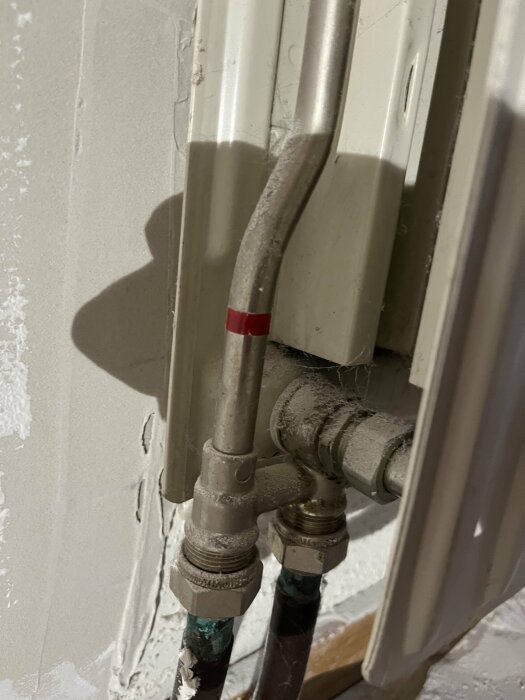 Radiatoranslutningar, vattenledningar, ventiler, vägg, dammigt, en röd markering, skugga, närbild, installation.
