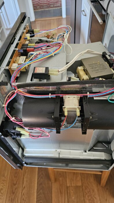 Intern vy av en öppen diskmaskin som visar elektriska komponenter och ledningar.