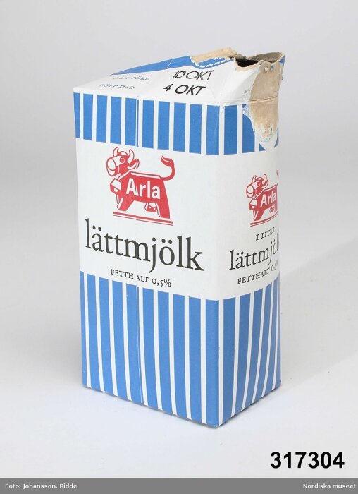 En gammal Arla lättmjölkskartong med blå ränder och utan kork.