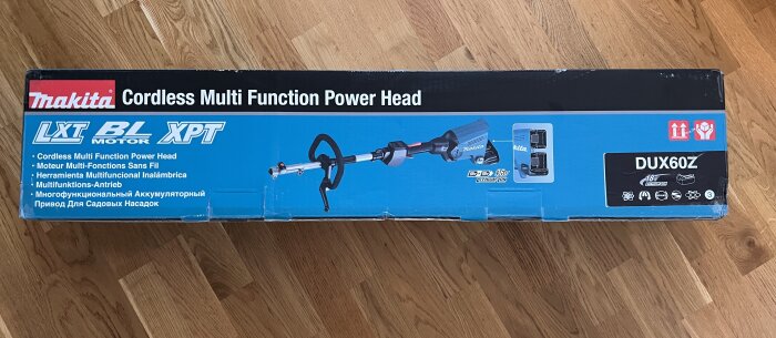 Förpackning av Makita DUX60Z Cordless Multi Function Power Head på ett trägolv.
