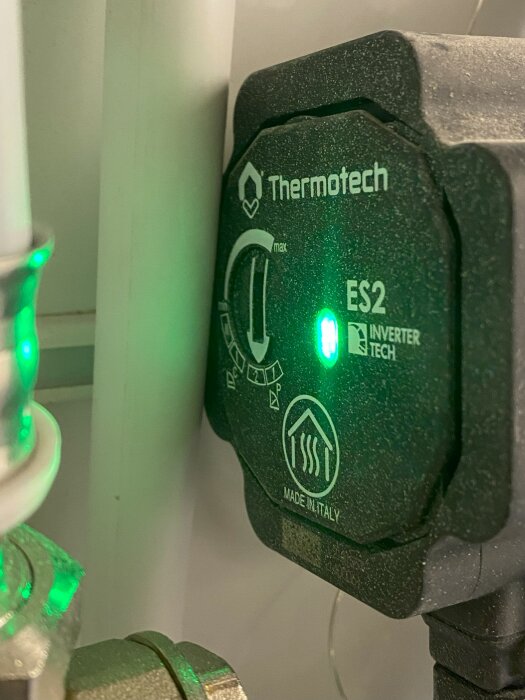 Thermotech värmeregulator med grön lysdiod och inställningsratt i en värmesysteminstallation.