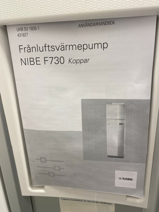 Användarhandbok för frånluftsvärmepumpen NIBE F730 fäst på en vit vägg.