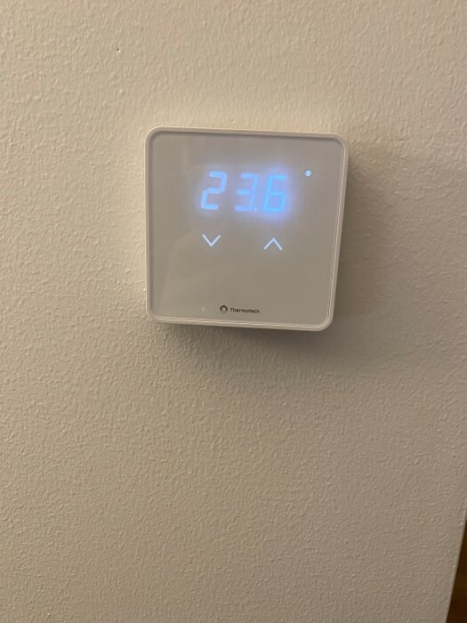 Thermotech termostat visande 23.6 grader med pilar för temperaturinställning.