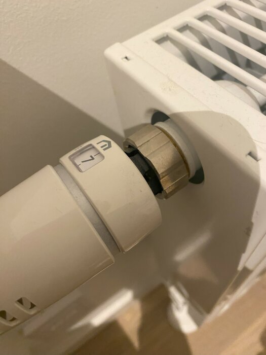 Närbild på en vit Purmo-radiator och termostatinställning i ett radhus, inställd på maximal värme.