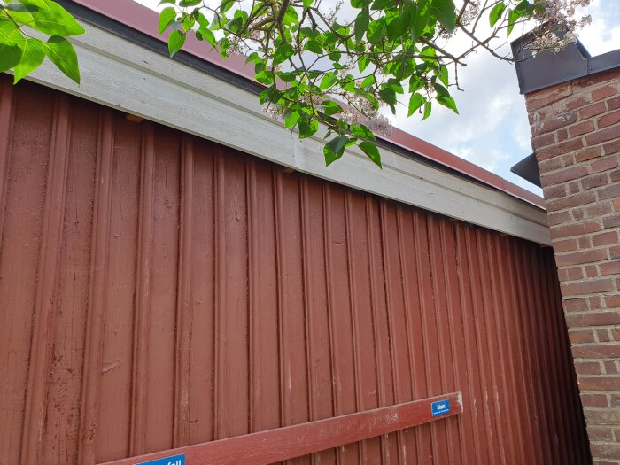 Tilted brick building leaning towards a red wooden structure with visible cracks and a slight overlap at the roof edge.