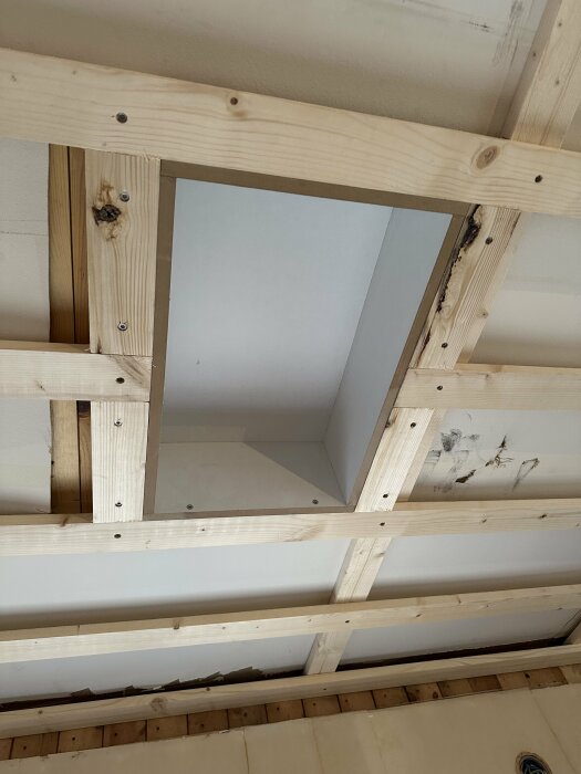 Träreglar monterade i taket för läktning med synlig högtalarlåda och bärande balk i ett kök under renovering.