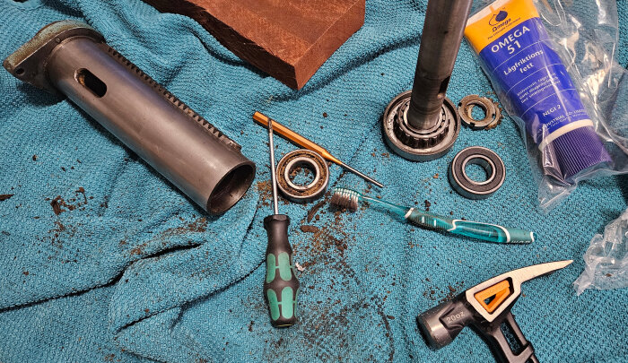 Isärtagna delar av en maskinspindel med lager och verktyg på en blå handduk.