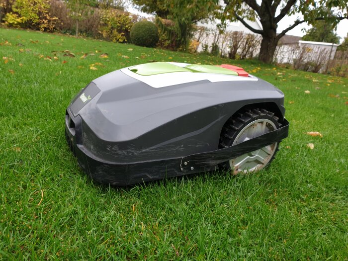 Robotgräsklippare 'Ville' med avbärare på gräs med löv, redo att rengöras och tas i bruk.