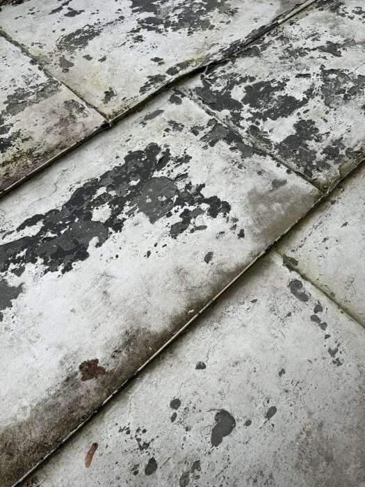 Slitna betongplattor med flagnande färg och ojämnt underlag som behöver renoveras.