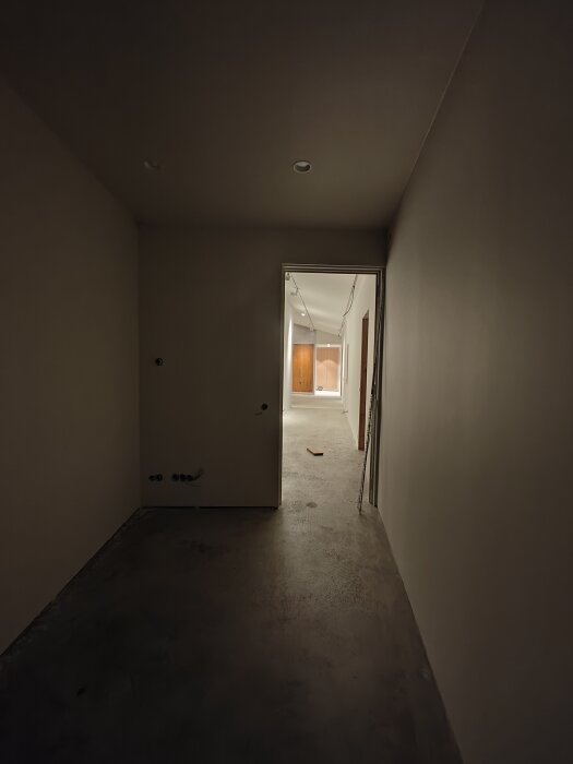Ett nyrenoverat rum med slipat betonggolv, klart för läggning av nytt golv, med installationsuttag i väggarna.