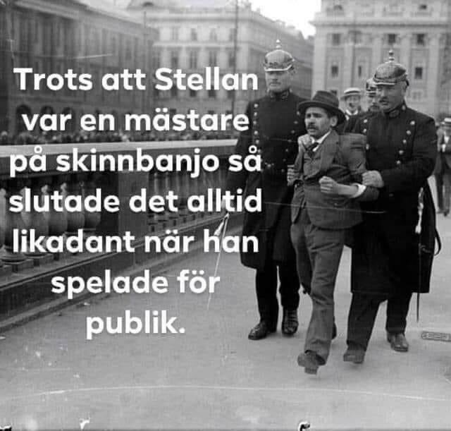 Svartvit bild av tre män som går, en spelar dragspel, eskorteras av två poliser.